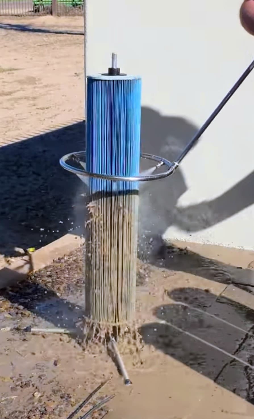A pool pro standing upright, moving the Halo360 around a cartridge filter as dirt washes out of the pleats